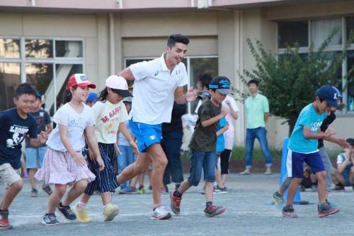 選手と児童が一緒に校庭で競歩している写真