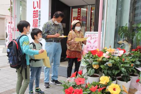 花屋の店先でヒントを探す家族連れの参加者