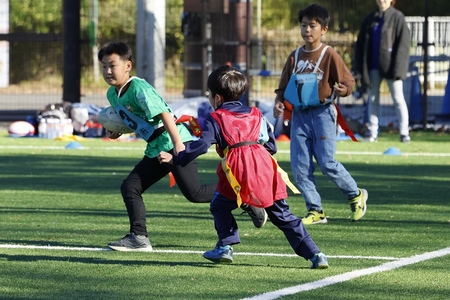 タグラグビーで腰につけた「タグ」を奪い合う子どもたち