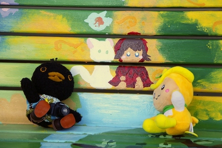 「青い目の人形」が描かれたベンチに座るトコろんとひばりちゃんの画像