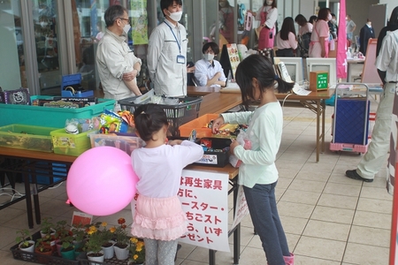 風船を持った女児たちが展示品を選ぶ様子