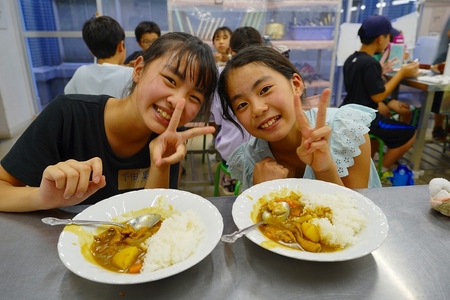 机に並べられたカレーと子どもたちの写真