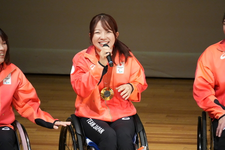凱旋報告会にて、舞台上で笑顔で話す田中選手