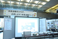 市民ホールに設置したスクリーンに活動を紹介する動画が流れている画像