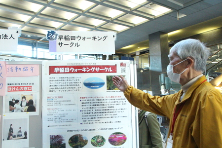 展示を指さしながら説明している人の画像