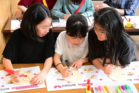 友達3人が並んでラケットに絵を描く様子