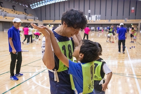 親子が笑顔でハイタッチしている画像