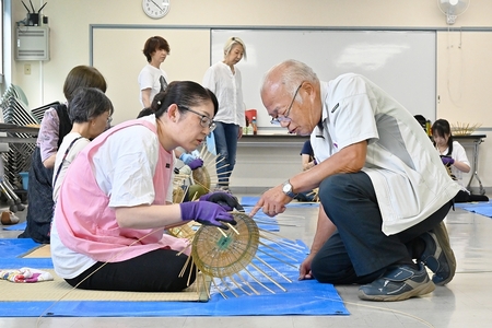 参加者が編んでいるところに講師が指導している。