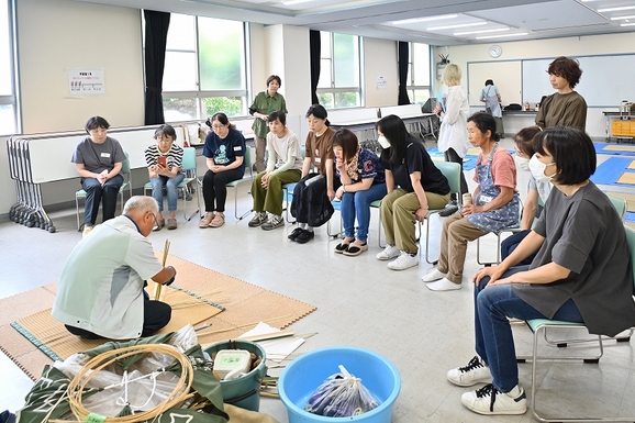 講師の先生が安松ざるを編んでいるのを10名の参加者が囲んでみている。