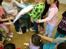 頭と尾のついた魚を、子供たちが抱えている写真です。