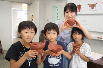 出来上がった土器とポーズをとる家族の写真