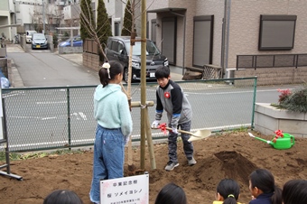 児童がスコップで土をかける様子の写真