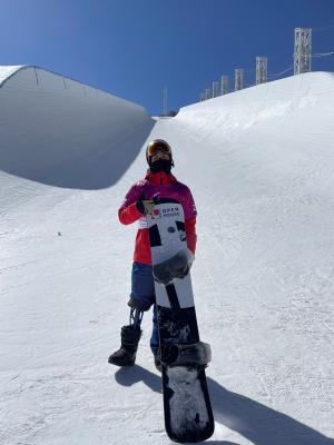 スノーボードを持って雪の上に立つ小須田さん