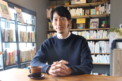 本棚の前に座る大竹さん