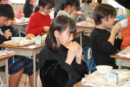 パンにハンバーグを挟んで食べる小学生の様子