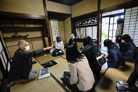 秋田家住宅内で明治時代の生活の様子を聞く参加者たち