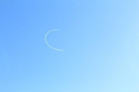空に現れた白い弧の飛行機雲