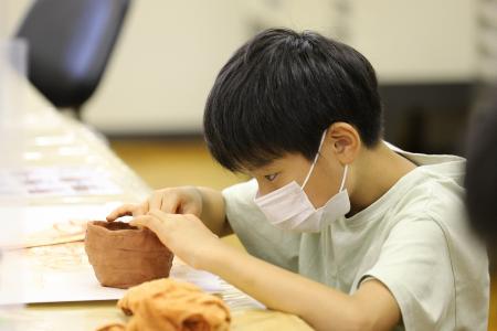 粘土で縄文土器を作る子ども