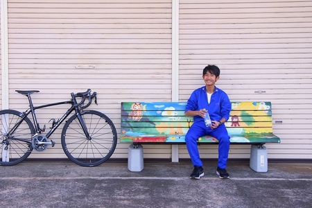 アートなベンチに座って水を飲む学生と自転車の画像