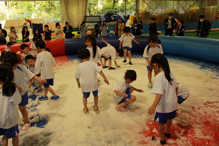 園児たちが雪が敷き詰められた巨大ビニールプールで遊んでいる