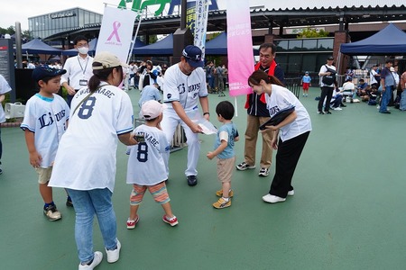 家族連れにグッズを渡すコーチ