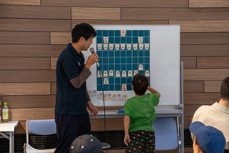 ホワイトボードに貼った大きな将棋盤を使って先生が説明している画像